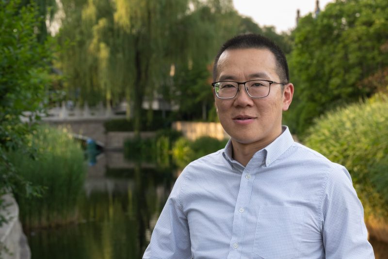 Portrait photo of Jonathan Cheng standing in front of a parkside river.