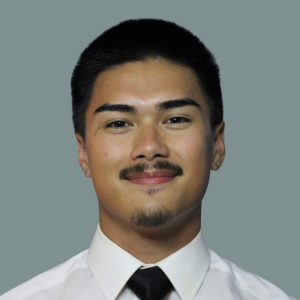 Elijah Tuncap in a white shirt and black tie smiling