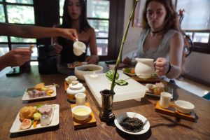 Students sit around a table for tea and food.