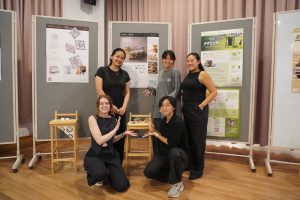 Students pose in front of project posters.