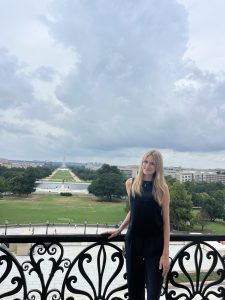 Woman in black dress standing outside. 