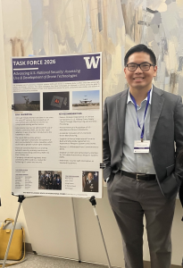 Man in suit standing next to academic poster