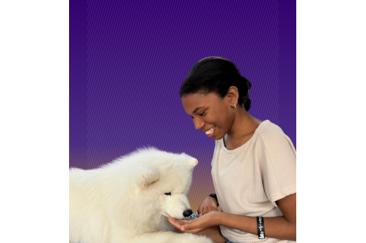 Photo of Kalisha Dent holding her hand up to the chin of a Samoyed