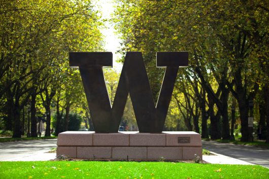 Bronze block W that stands at entrance to UW on NE 45th Street. In background is Memorial Way. Fall.