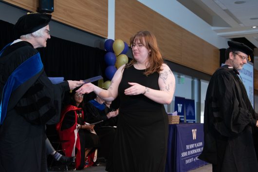 Mai Kearney receives her master's degree at the 2026 Jackson School Spring Convocation on June 13, 2026. To the right is Jackson School Japan Studies Program Chair and Professor Robert Pekkanen. Photo by Kerry Dahlen