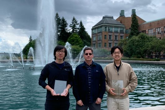 Left to right: Herman Chau, Paul S. Atkins and Michael Zeng pose in front of Drumheller Fountain at the University of Washington with the 2025 Jinmonkon Best Paper award and the Student Encouragement award