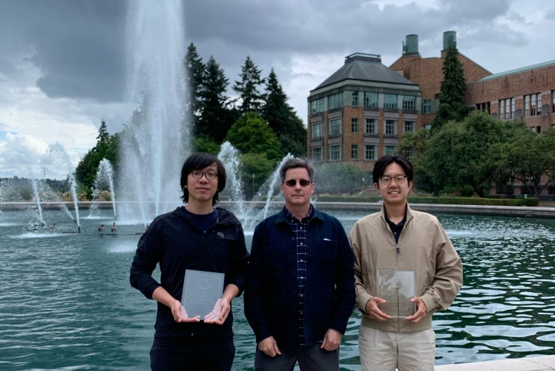 Left to right: Herman Chau, Paul S. Atkins and Michael Zeng pose in front of Drumheller Fountain at the University of Washington with the 2025 Jinmonkon Best Paper award and the Student Encouragement award